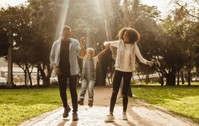 Image of a couple each holding one of their young child’s hands and swinging him playfully between them